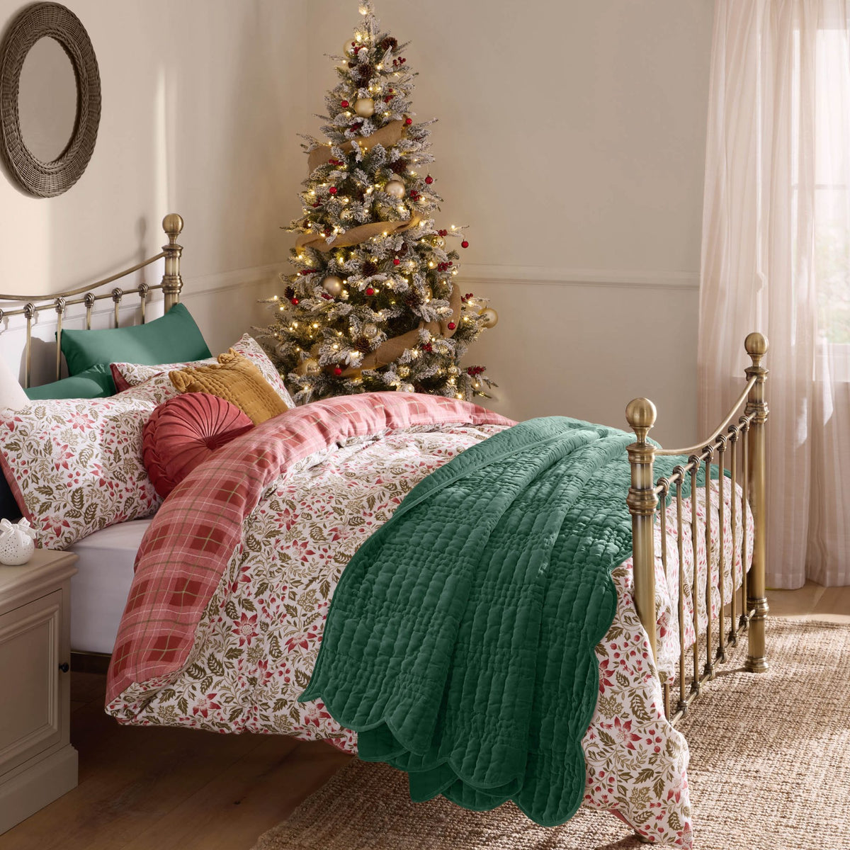 Cozy bedroom featuring a decorated Christmas tree and patterned bedding with a green quilt.