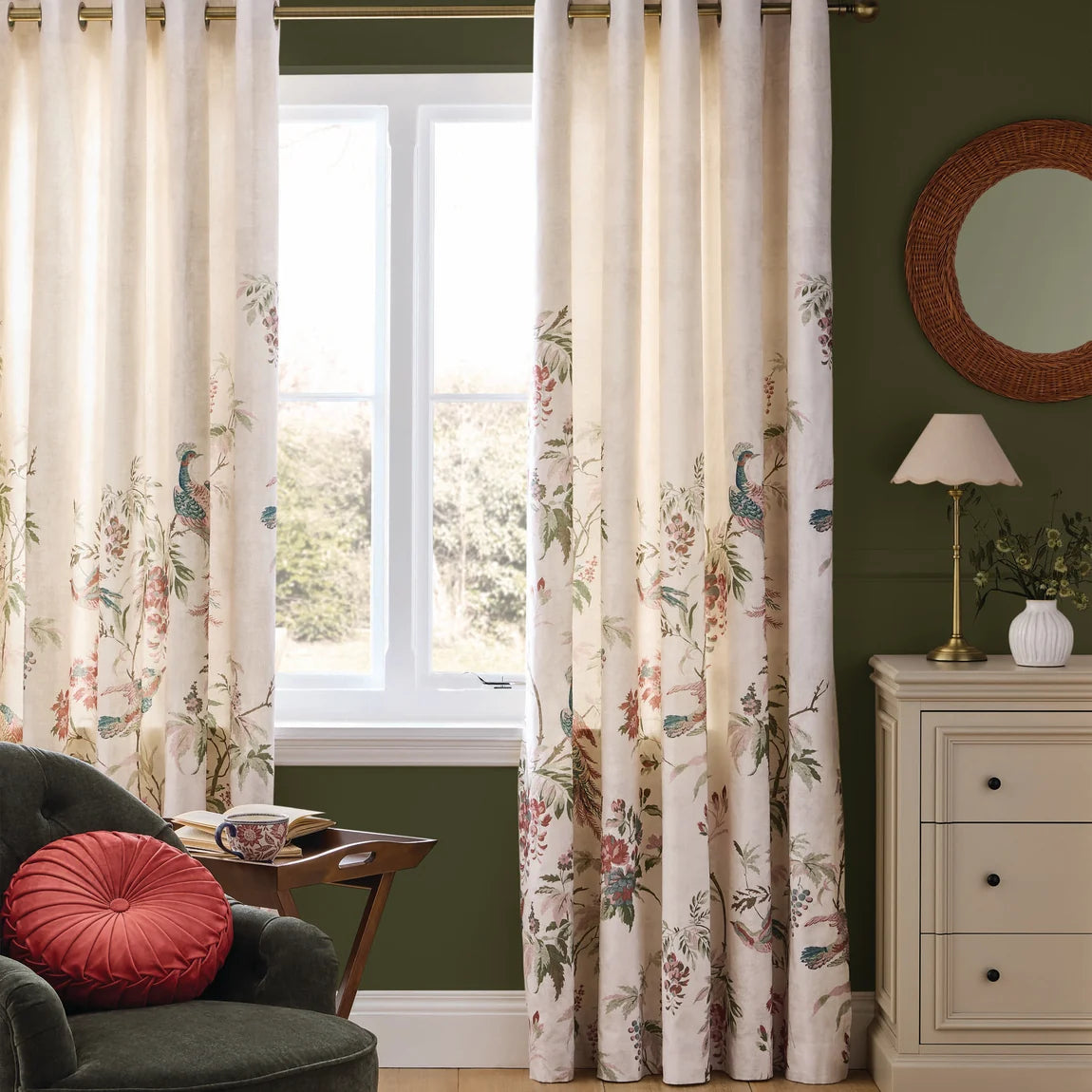 Cream floral patterned curtains with bird motifs hanging in a green living room.