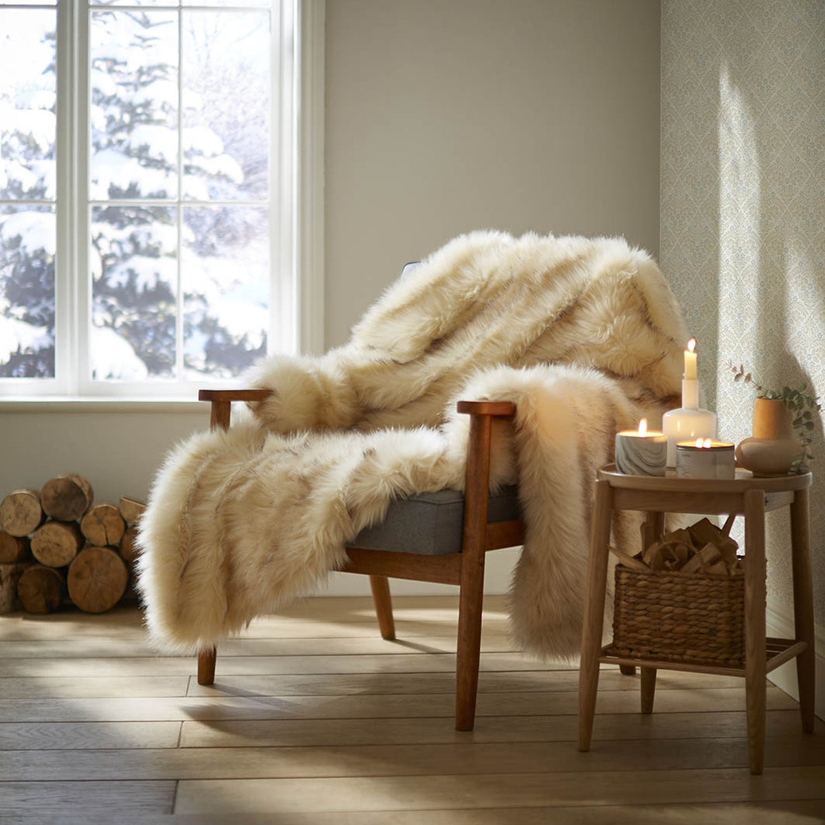 Cozy armchair draped with a cream faux fur throw next to a side table with candles.