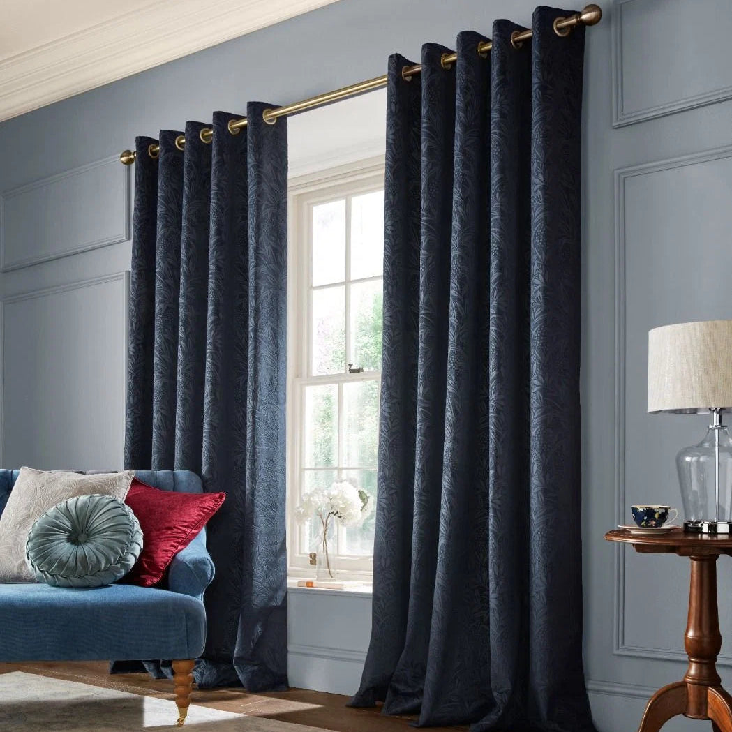 Navy blue patterned curtains hanging on a gold rod in a modern living room.